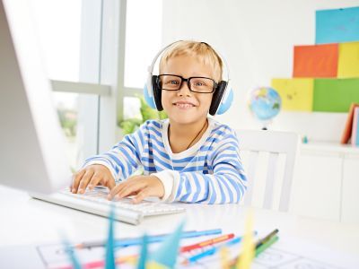 Child playing on computer, wearing headphones.