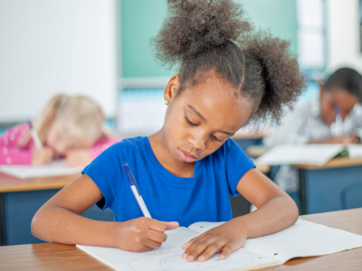 Child sitting at a desk writing. 