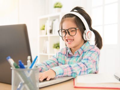 Child playing on computer, wearing headphones.