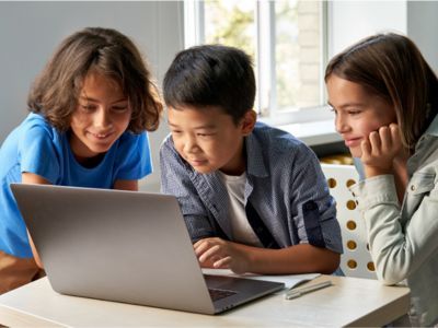 Three children working together on a laptop.