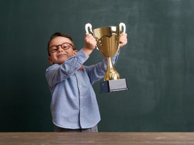 Child celebrating, holding a trophy.