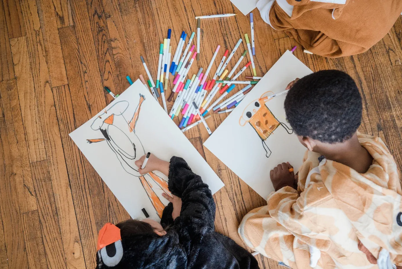 Two children, drawing characters.