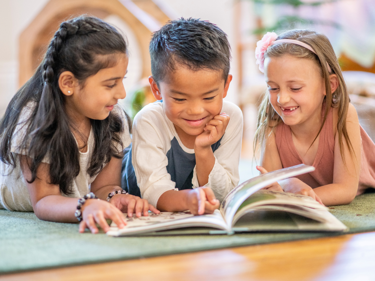 Three children reading a book together.