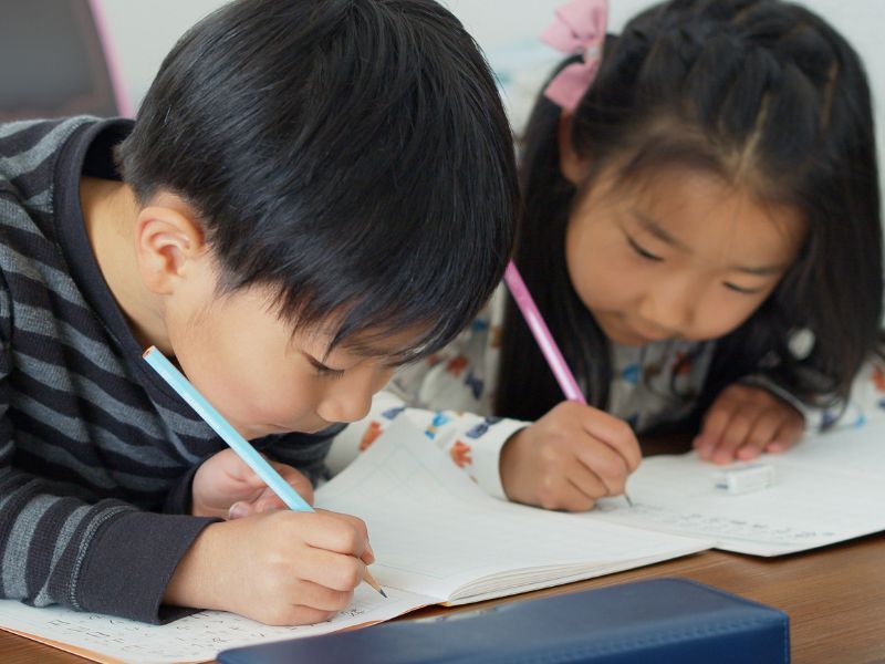 Two children, practicing their writing.