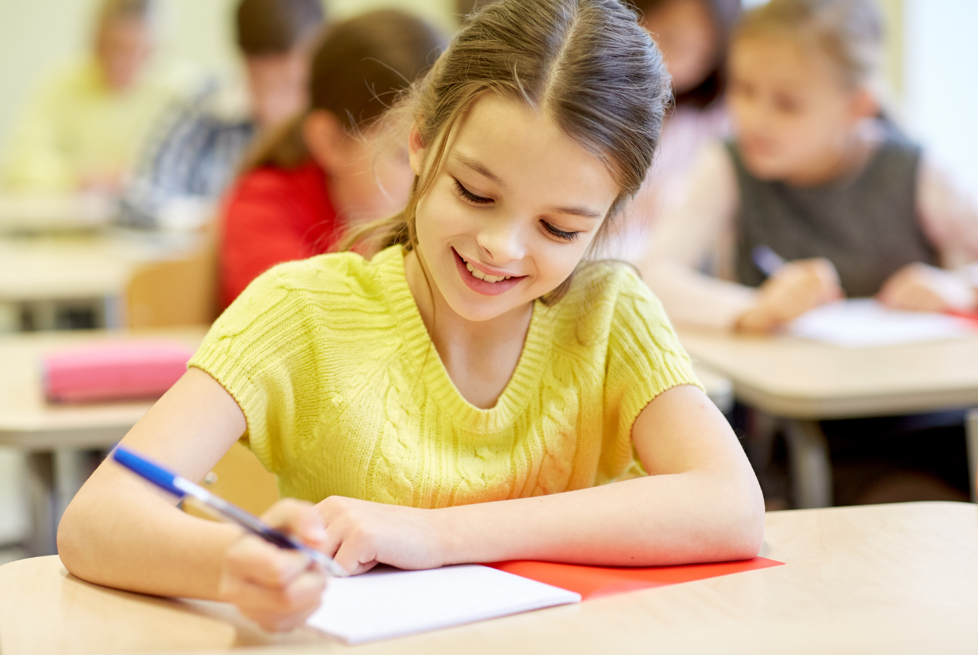 Girl writing happily in class.