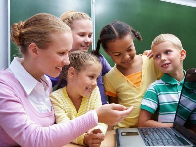 Teacher and students looking at a laptop screen.