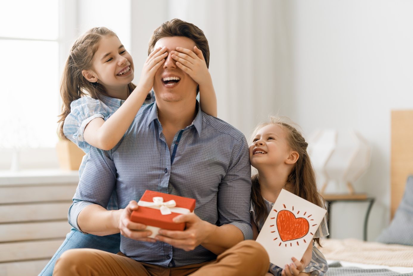 Two children giving a Father's Day gift and card to their father.