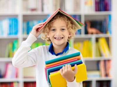 Child holding a book above his head and smiling.