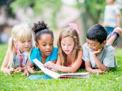 Children reading together in the grass.