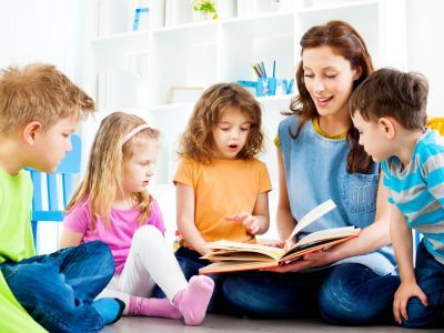 Teacher and students, reading a book.