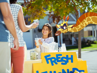 Sam the giraffe with a child selling lemonade at a homemade stand. 