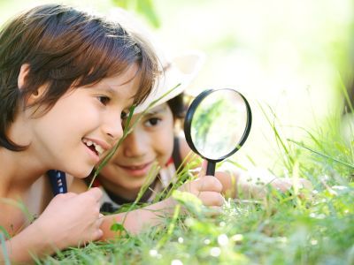 Children looking at grass through a magnifying glass.