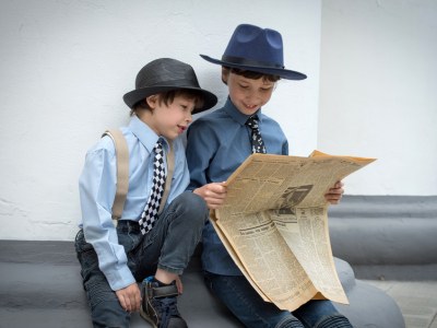 Two children, dressed as reporters, reading a newspaper.