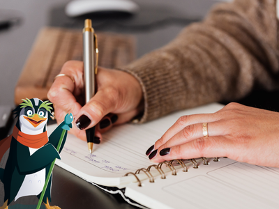 Hand holding pen writing in notebook.
