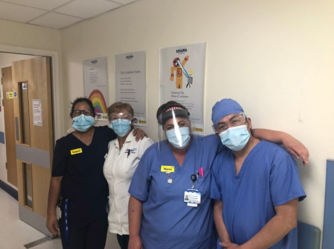 Nurses posing in front of Caring Stars entries, displayed in hospital corridor.