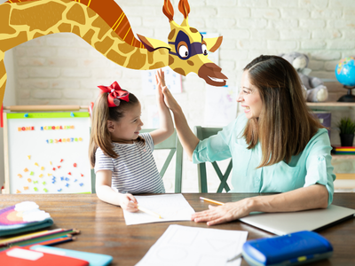 Child and mom sitting at desk, high five-ing and smiling with Sam the Giraffe.